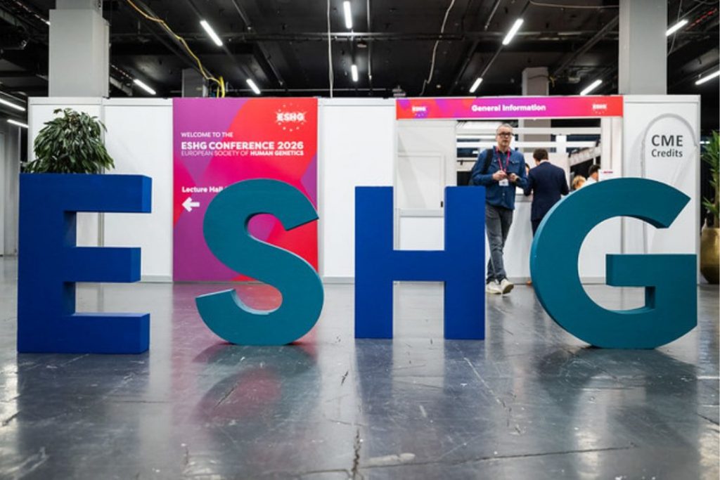 Large freestanding ESHG letters at the entrance of the European Society of Human Genetics Conference 2026, with conference signage, registration, and information desks visible in the background.